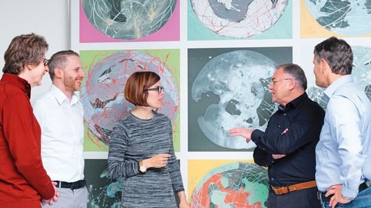 Des employés de TRUMPF discutent devant une peinture 