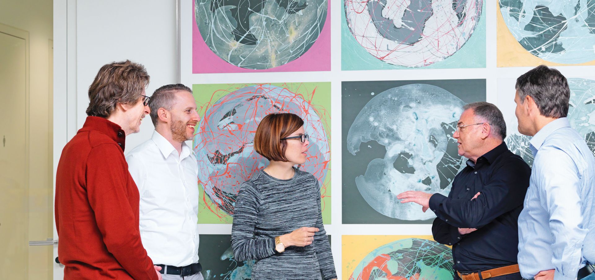 TRUMPF employees talking in front of part of a painting 