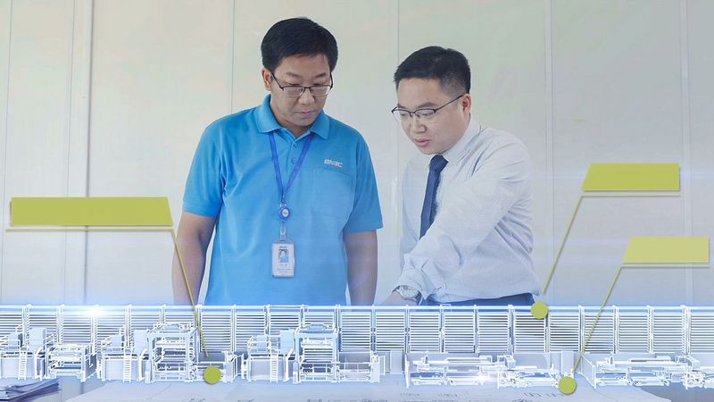 Des collègues devant une maquette miniature de la production